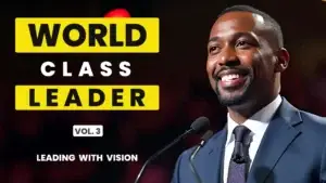 Charismatic speaker in a suit next to bold yellow and white text reading “World Class Leader Vol. 3 Leading with Vision” on a stage setting
