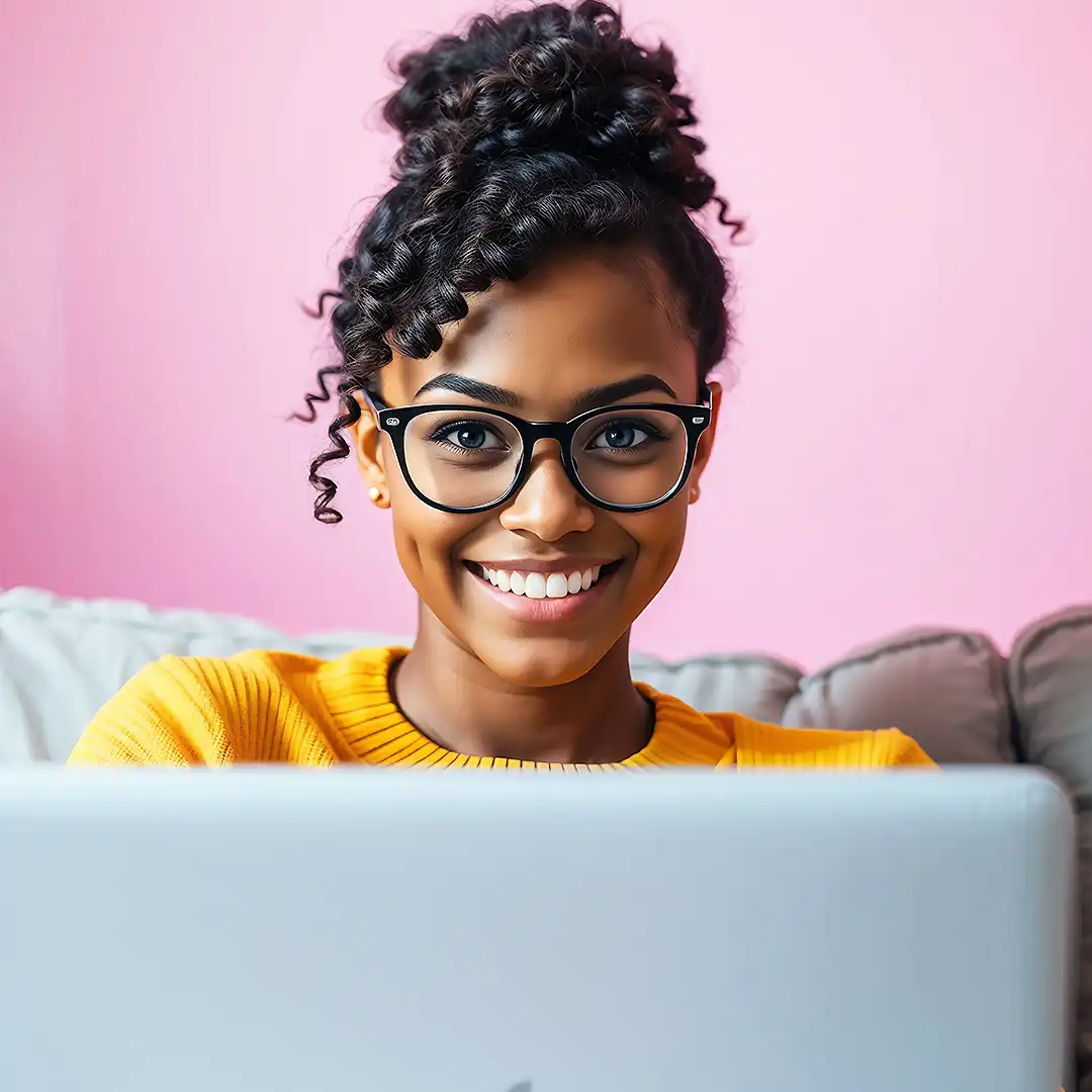 Smiling woman with curly hair and glasses using a laptop